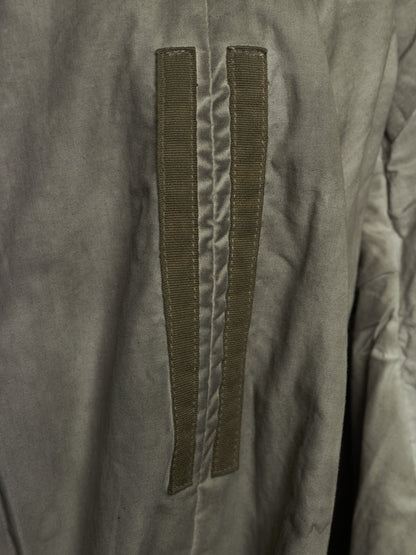 Close-up of a gray fabric garment featuring two vertical olive green hook-and-loop strap details on the front.