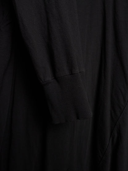 Close-up of a black long-sleeve garment with a ribbed cuff, showing soft fabric folds and texture.