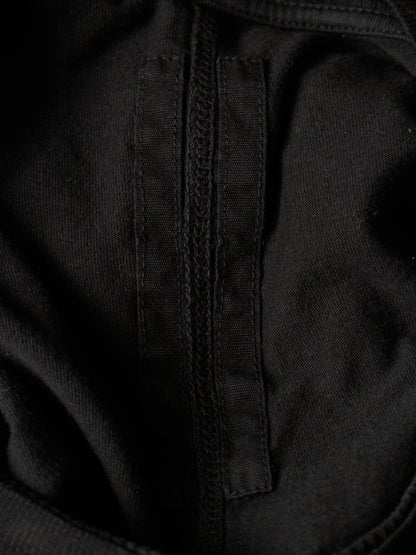 Close-up detail of a black fabric garment showing a vertical stitched seam and textured woven material.