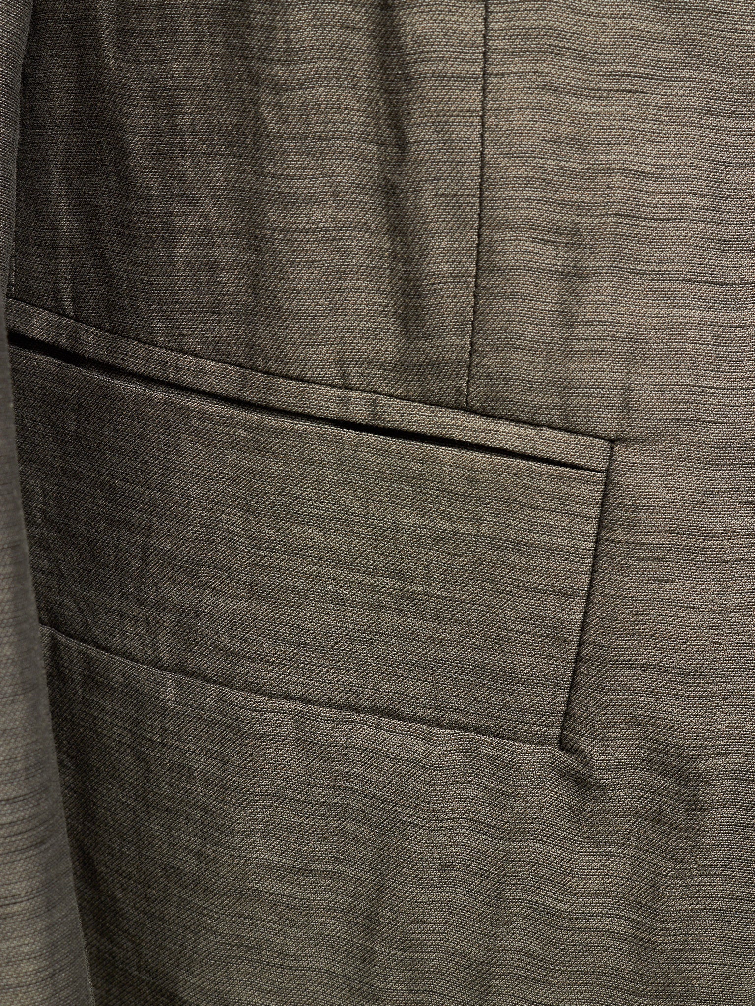 Close-up of a textured gray fabric jacket with a single welt pocket and fine woven horizontal lines.