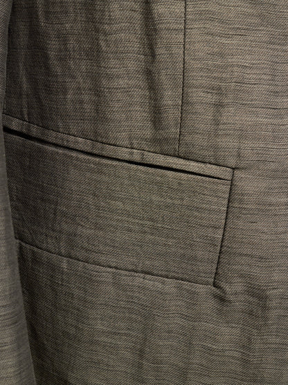 Close-up of a textured gray fabric jacket with a single welt pocket and fine woven horizontal lines.