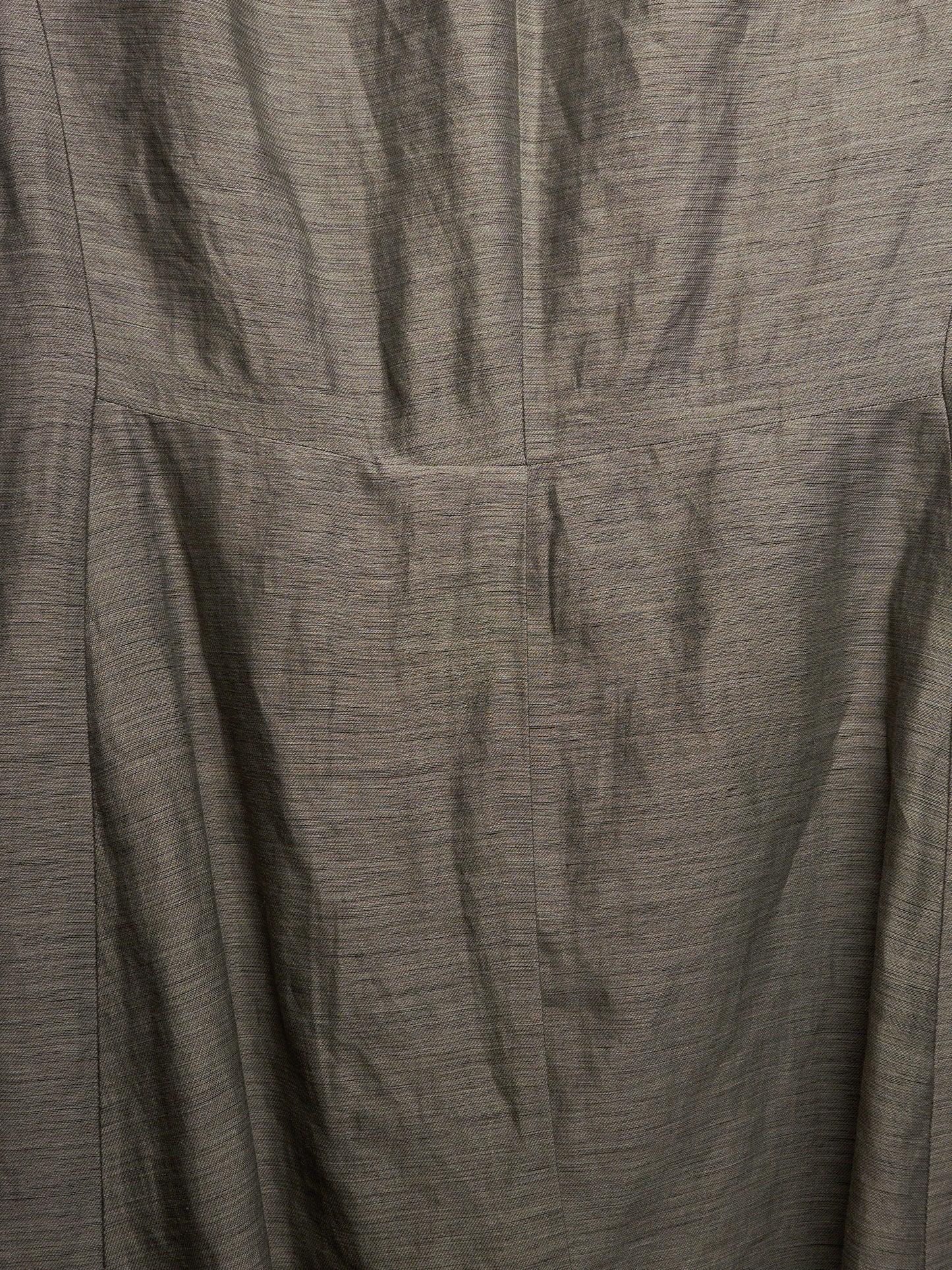 Close-up of a textured gray fabric with a fine slub or linen-like weave, showing folds and a vertical seam.