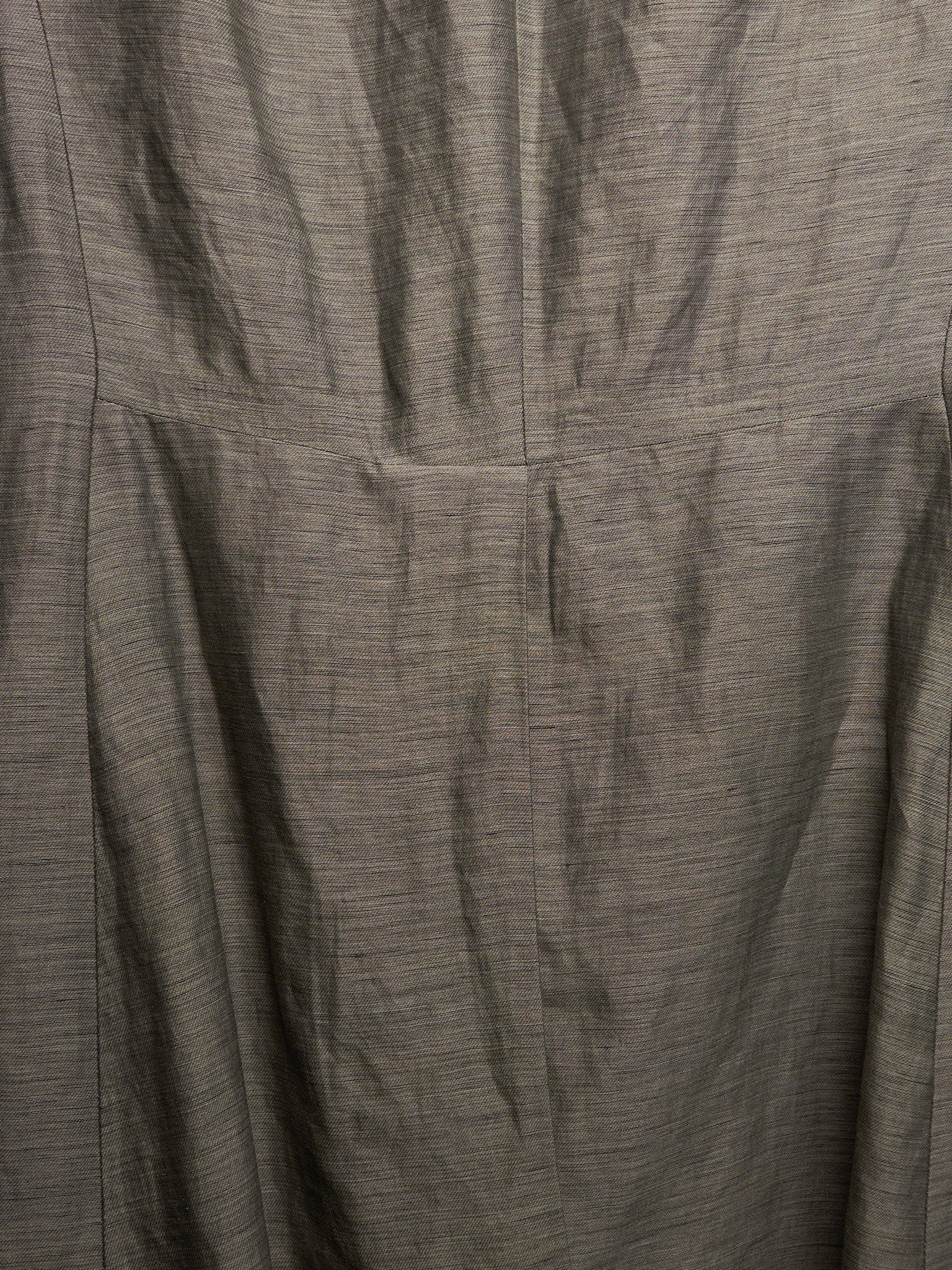 Close-up of a textured gray fabric with a fine slub or linen-like weave, showing folds and a vertical seam.