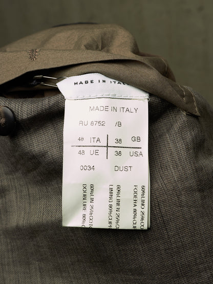 Close-up of a garment's interior label reading 'MADE IN ITALY' with size and country codes, attached to a dark brown textured fabric.