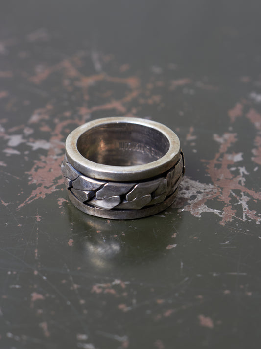 Silver ring with textured design on a dark surface