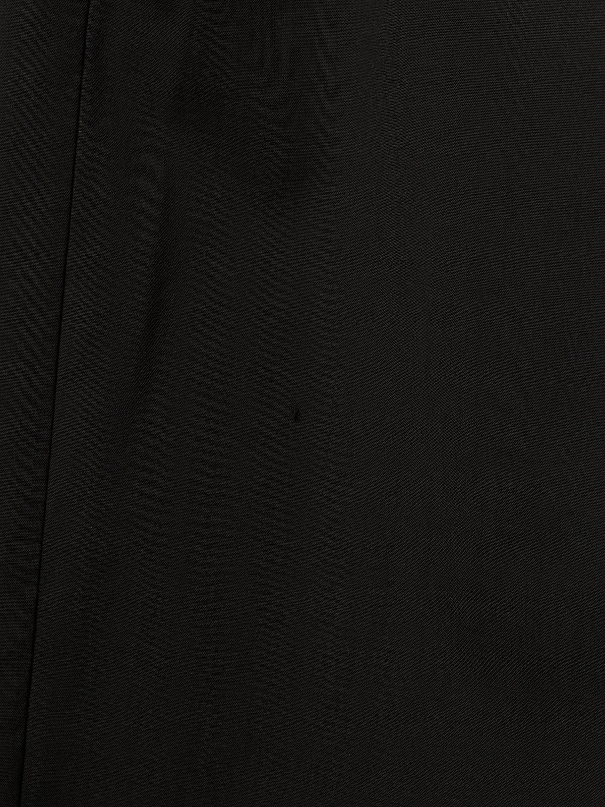 A close-up of a solid black textured material, likely a dark woven fabric or leather, with a subtle vertical seam on the left side.