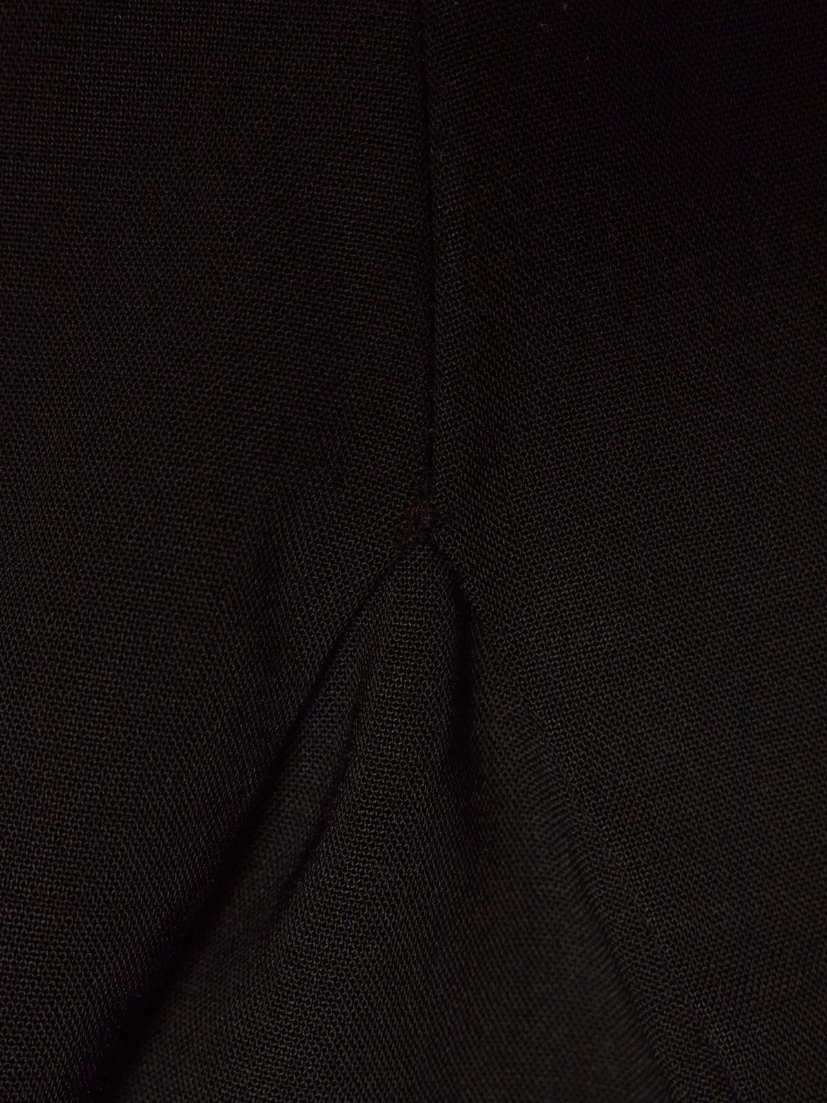 Close-up of a black textured fabric with a visible central seam and fold.