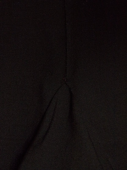 Close-up of a black textured fabric with a visible central seam and fold.
