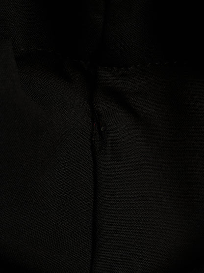 Close-up of a black textured fabric with a central seam and subtle stitched detail.