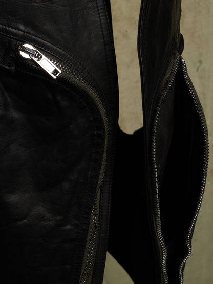 Close-up detail of a black leather jacket showing a silver zipper pull and an open zippered pocket.