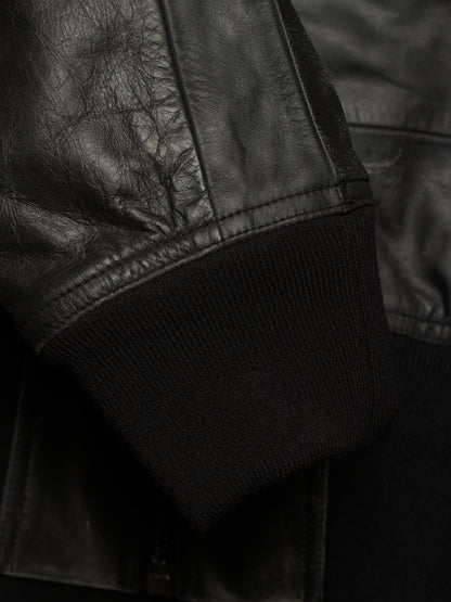 Close-up detail of a black leather jacket sleeve with a ribbed black knit cuff.