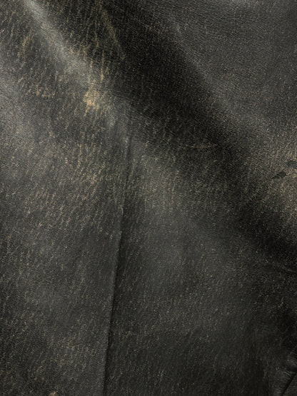 A close-up of dark textured leather with a subtle sheen and visible grain, filling the entire frame.
