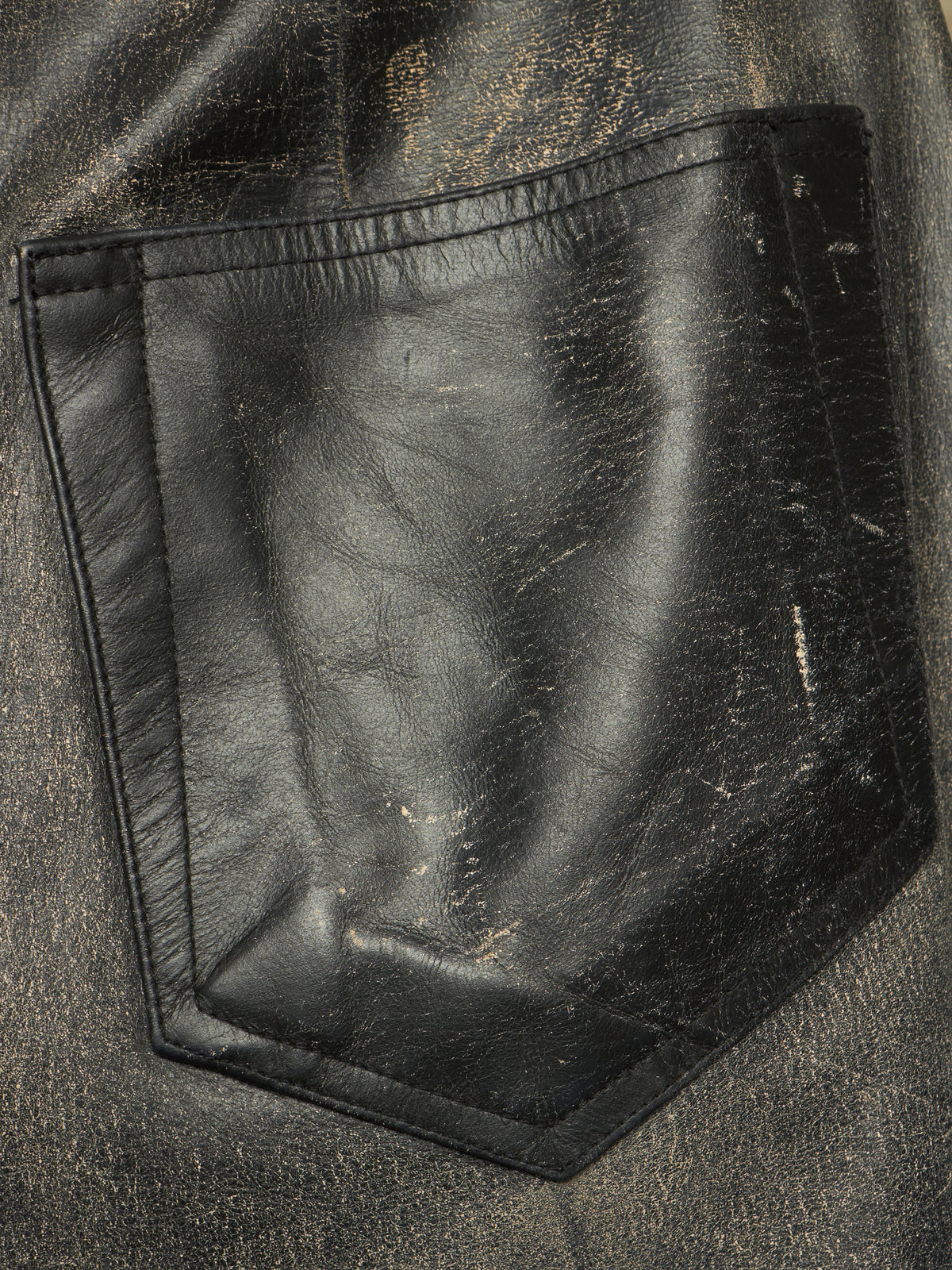 Close-up of a black leather pocket on a distressed black jacket, showing the texture and scuffing details.