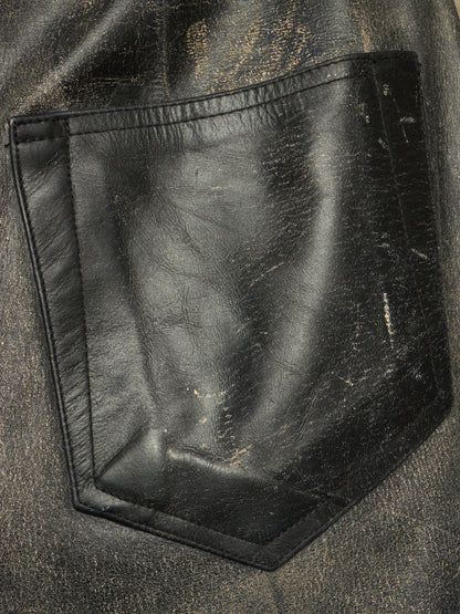 Close-up of a black leather pocket on a distressed black jacket, showing the texture and scuffing details.