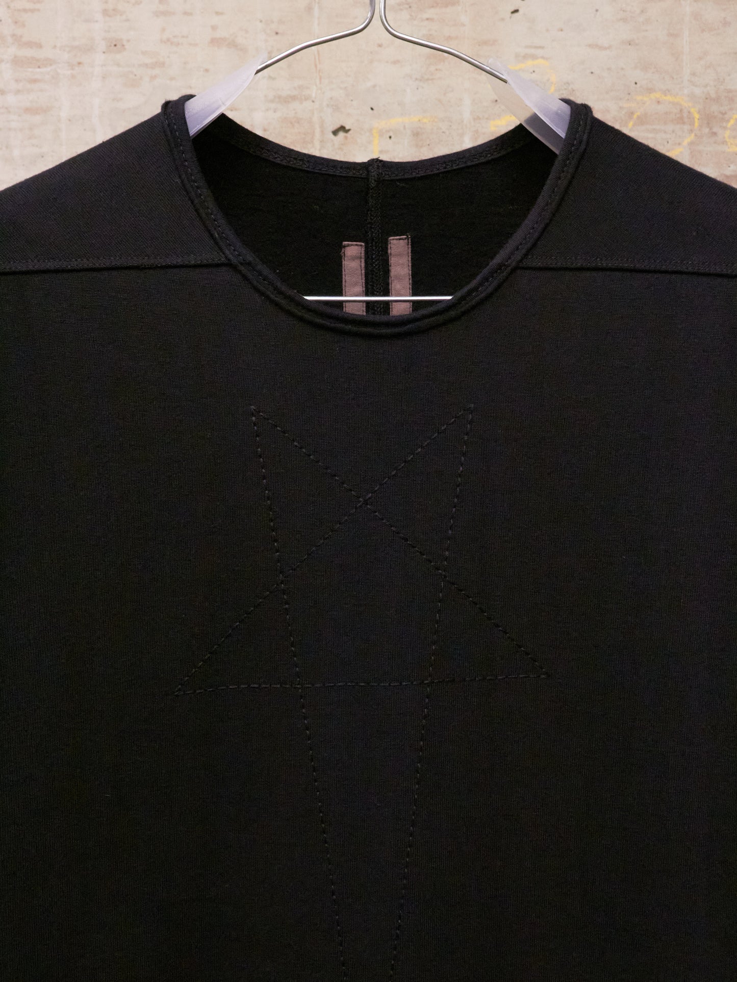 Black shirt on a hanger against a textured beige background