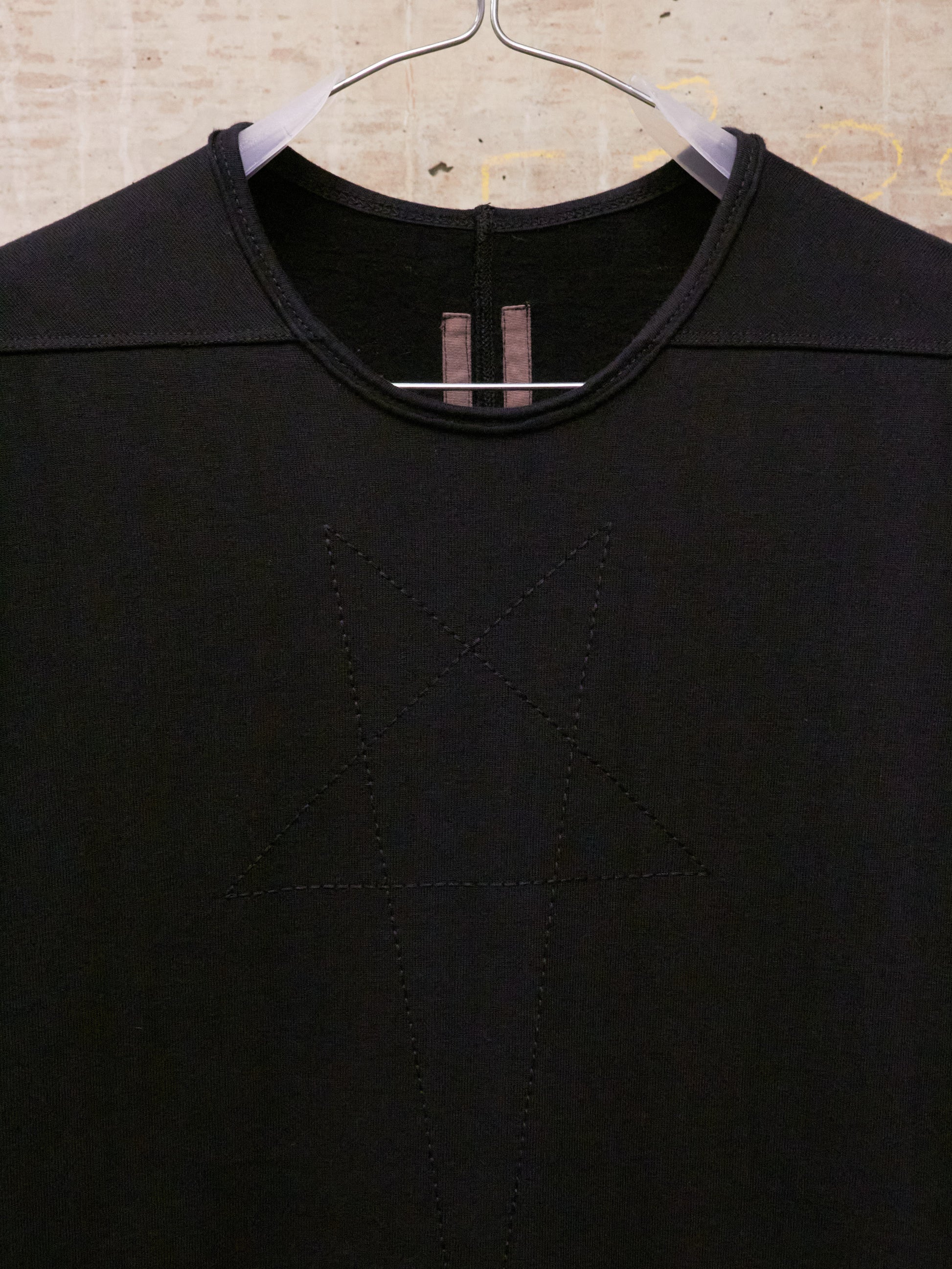 Black shirt on a hanger against a textured beige background