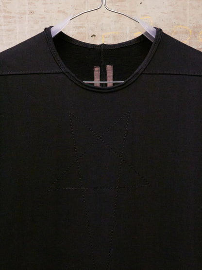 Black shirt on a hanger against a textured beige background