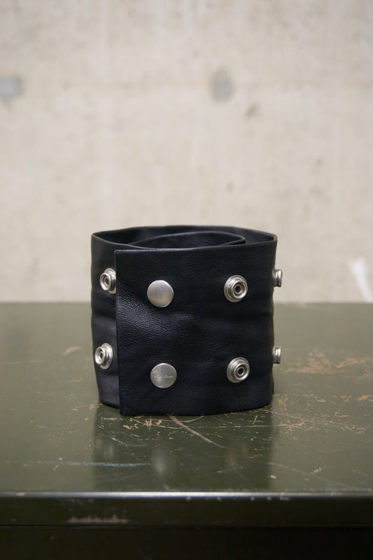 Black leather cuff with silver studs on a textured surface