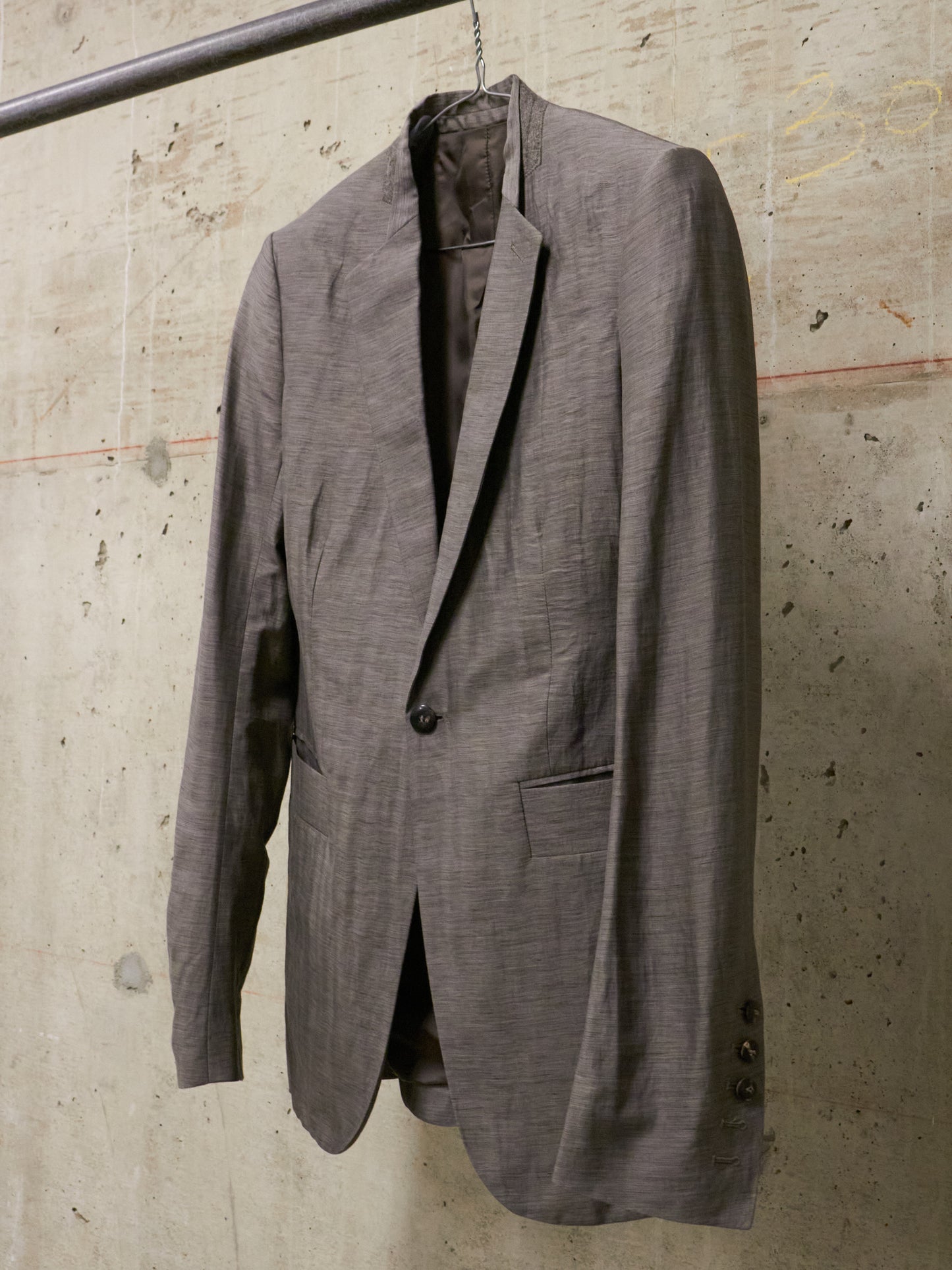 Gray suit jacket hanging against a textured wall