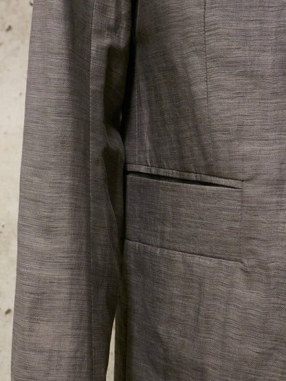 Close-up of a gray textured fabric with a pocket detail on a neutral background