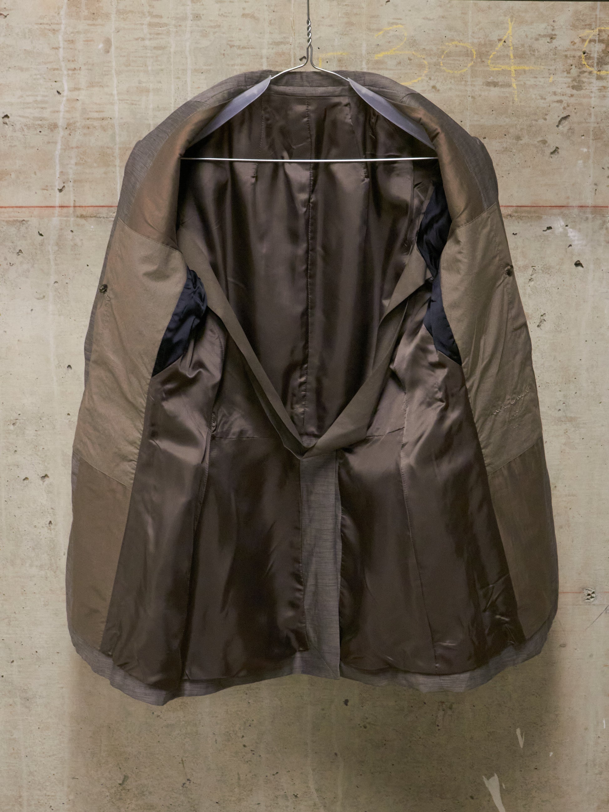Brown raincoat hanging on a textured wall