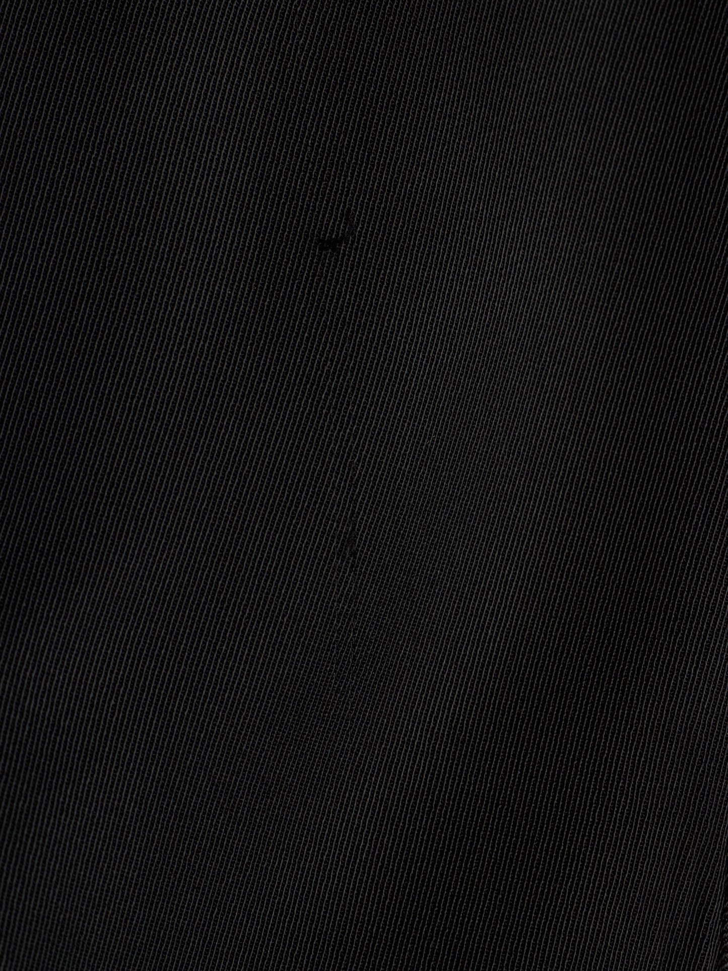 A close-up of a black textured fabric with a fine diagonal twill weave pattern.