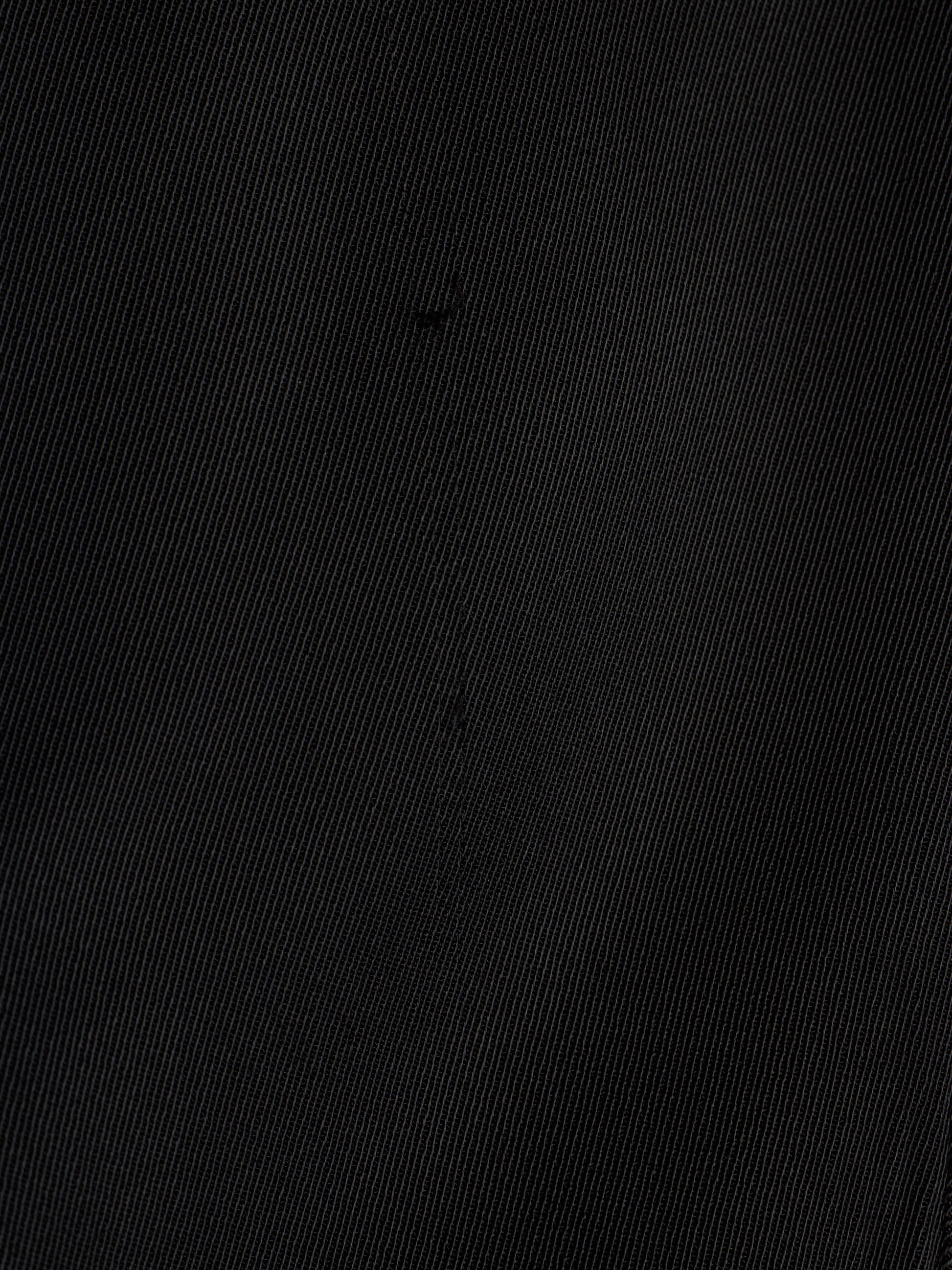 A close-up of a black textured fabric with a fine diagonal twill weave pattern.