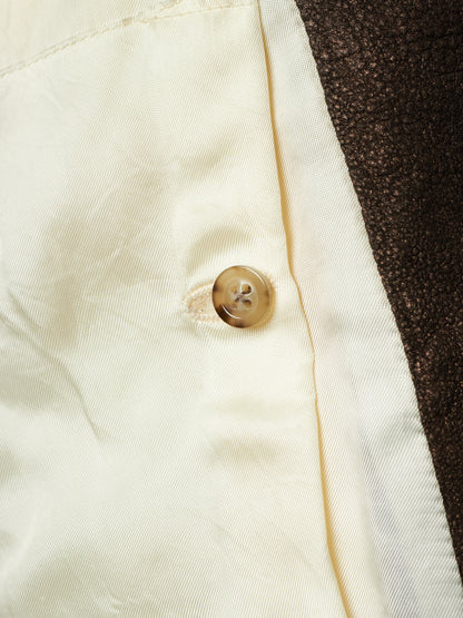 Close-up detail of a cream-colored satin-like fabric with a single brown button, next to a dark brown textured fabric.