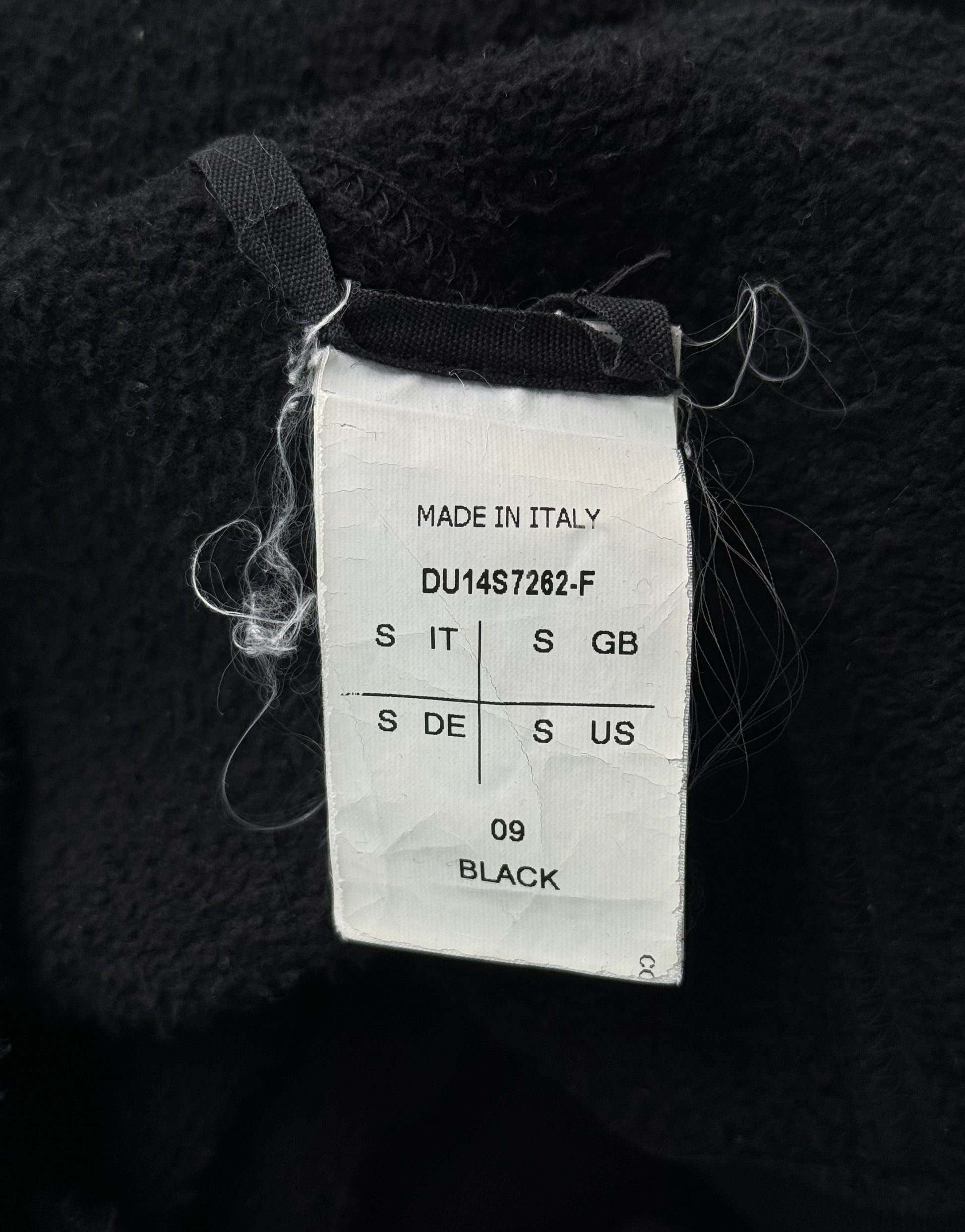 Clothing tag on a black fabric background with 'Made in Italy' text.