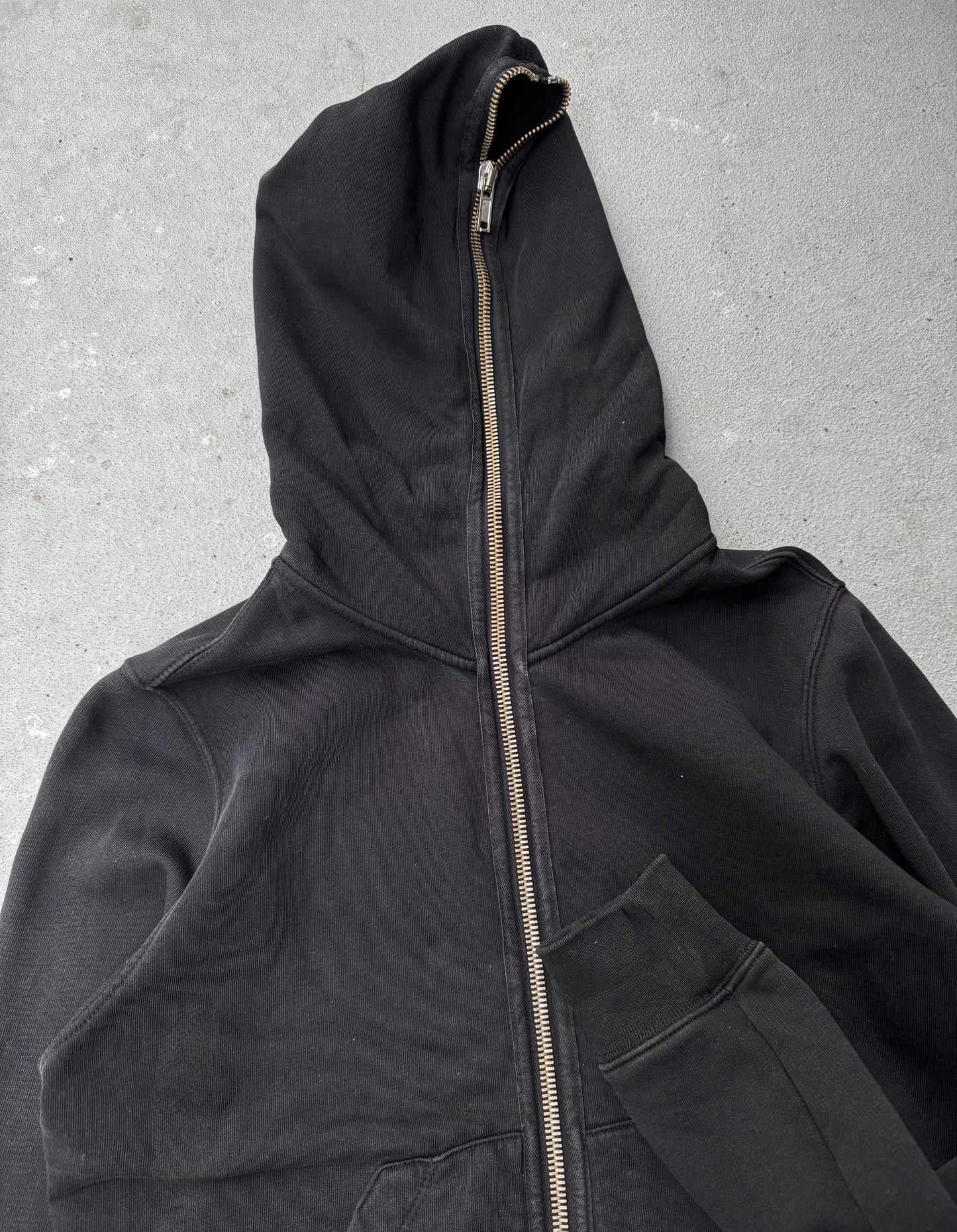 Black hooded jacket with a zipper on a gray background