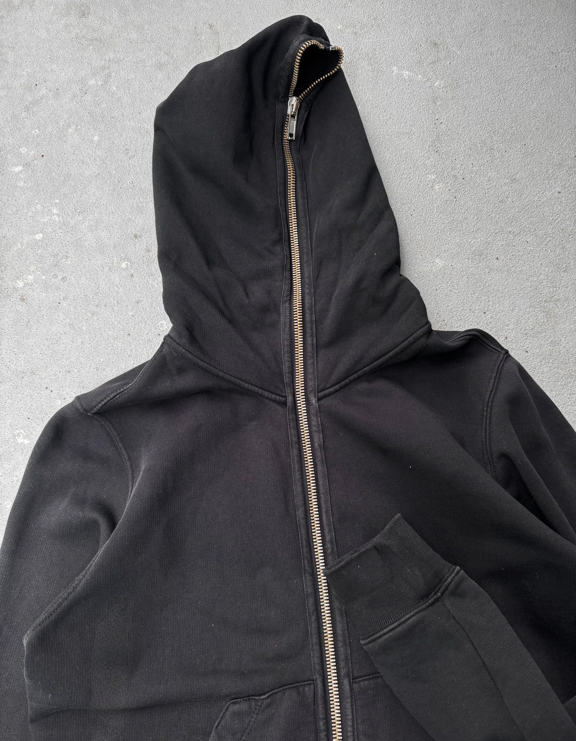Black hooded jacket with a zipper on a gray background