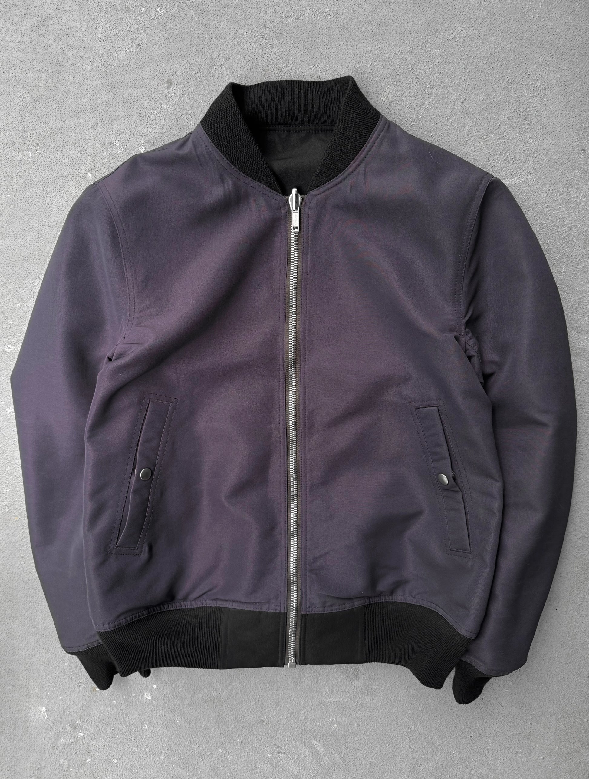 Purple bomber jacket with black trim on a gray background
