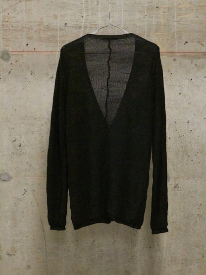Black sweater on a hanger against a textured beige wall