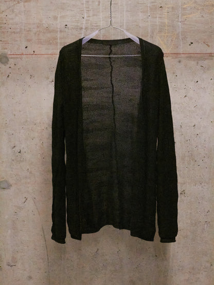 Dark gray cardigan on a hanger against a textured beige wall