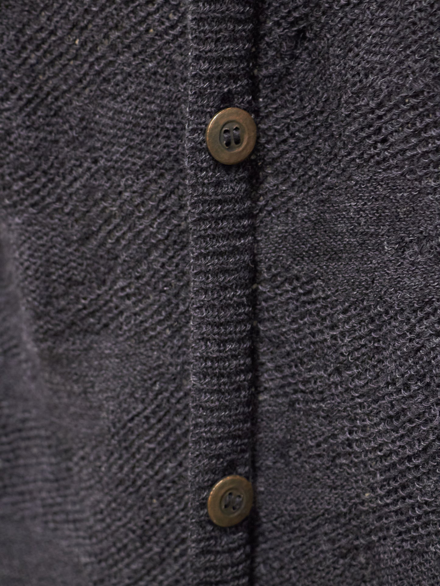 Close-up of a textured dark gray fabric with button details