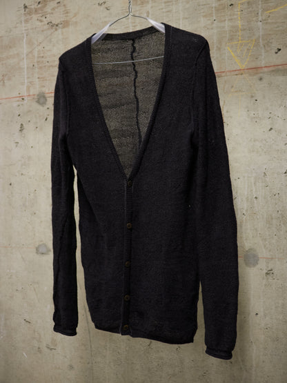 Black cardigan on a hanger against a textured beige wall