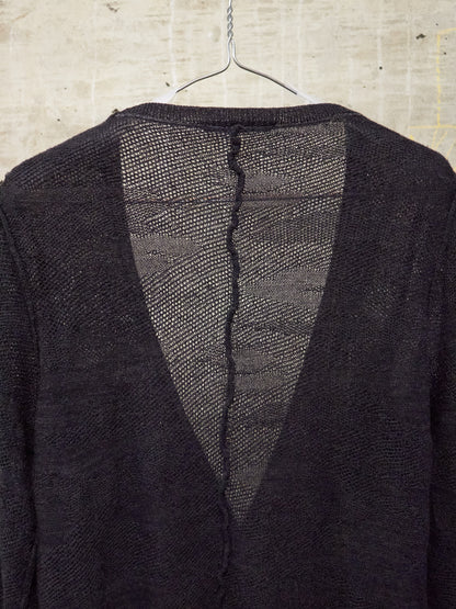 Dark textured jacket on a hanger against a concrete wall.