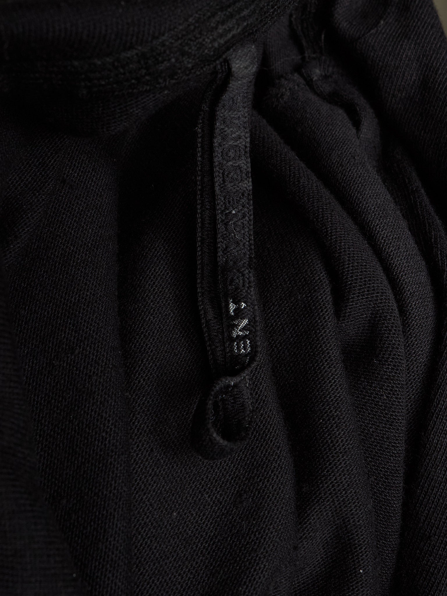 Close-up of a black textured knit garment with a matching black drawstring and a small white debossed brand name reading 'ENT' on the cord.