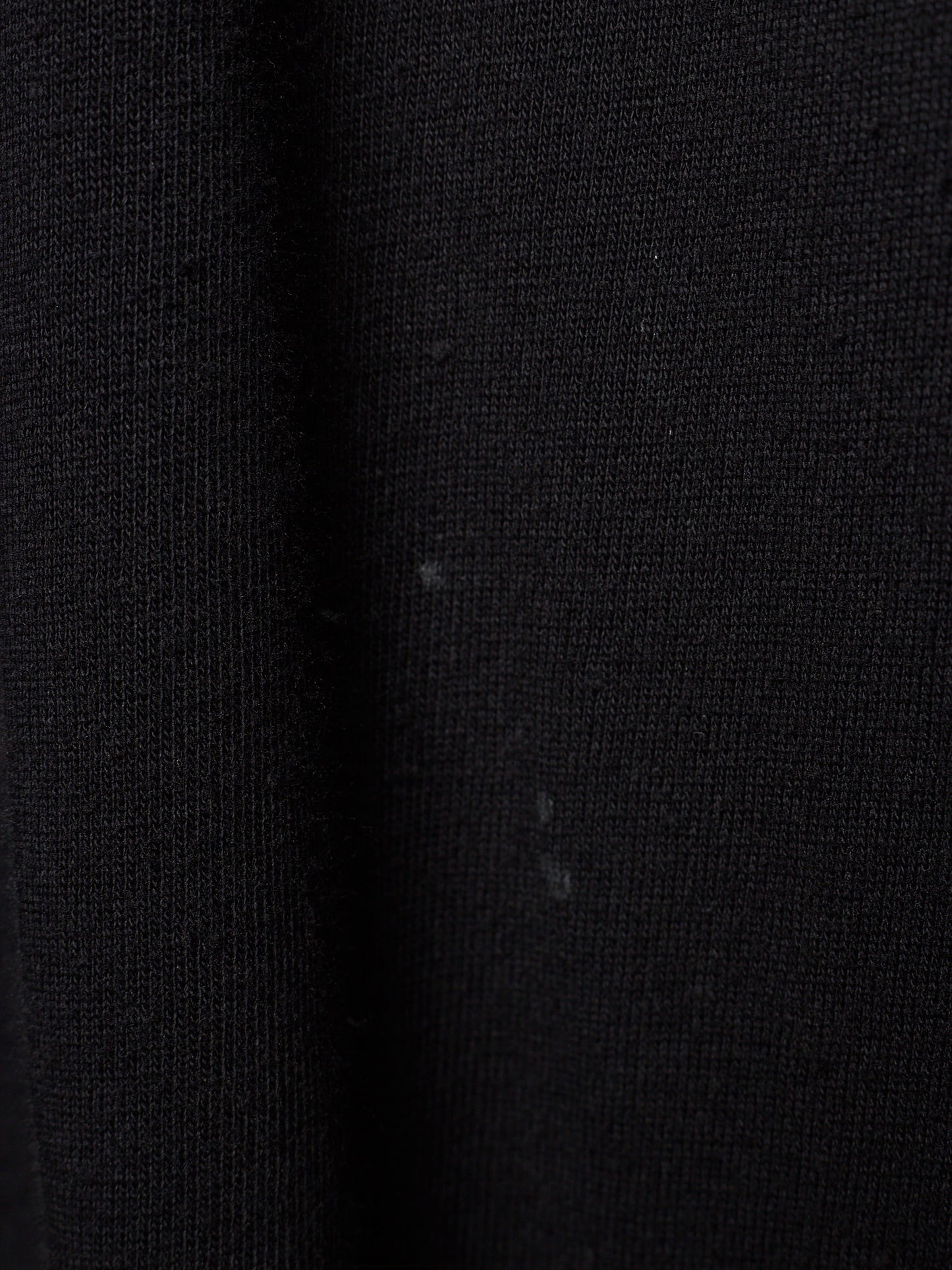 Close-up of a black ribbed knit fabric texture with a subtle sheen.