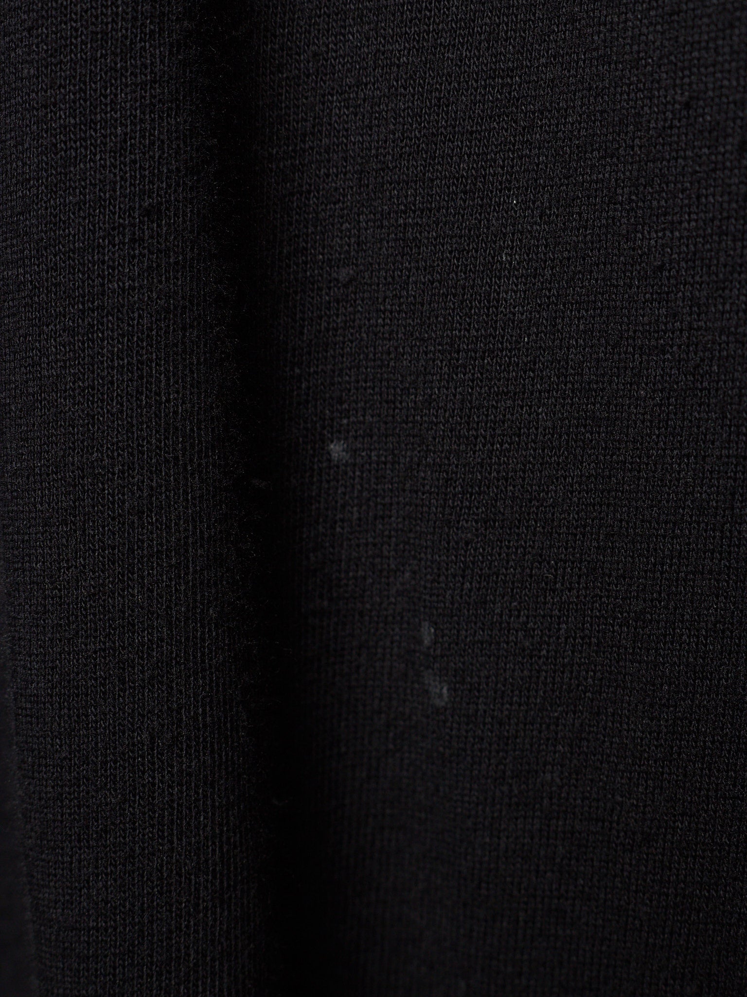 Close-up of a black ribbed knit fabric texture with a subtle sheen.