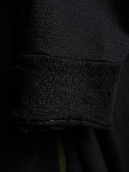 Close-up of a black ribbed knit cuff with frayed, distressed edges on a dark garment.