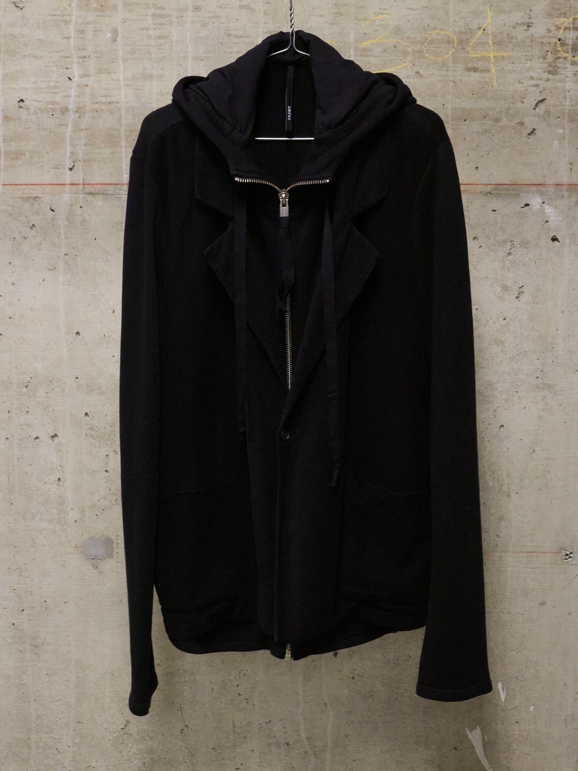 Black jacket on a hanger against a textured concrete wall