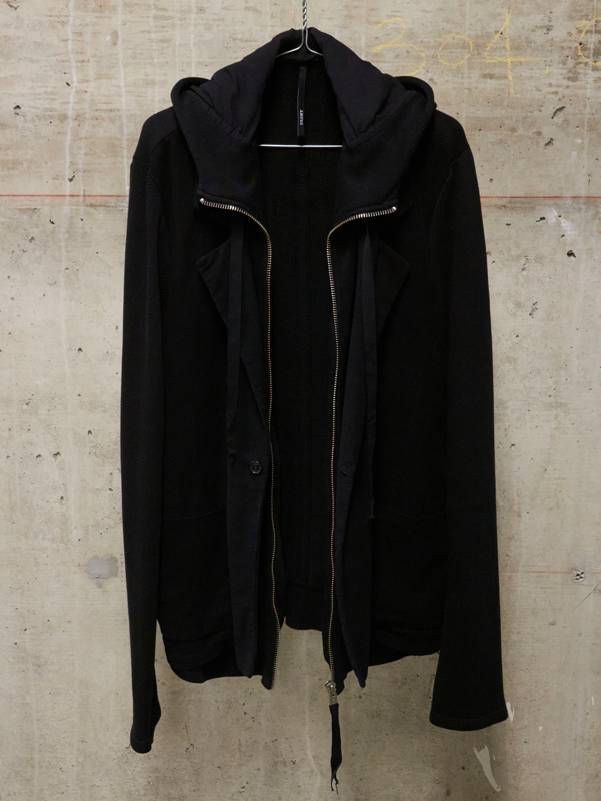 Black jacket on a hanger against a textured beige wall