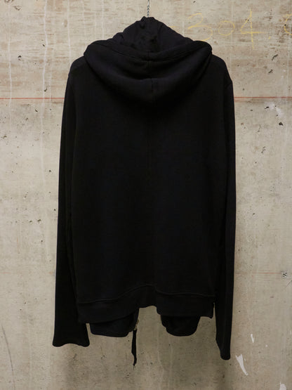 Black hoodie hanging on a textured beige wall