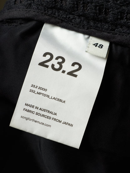Close-up of a black garment interior with a white size tag reading 23.2 and 48, plus text noting made in Australia and fabric sourced from Japan.
