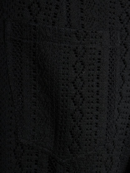 Close-up of a black textured knit fabric with a geometric openwork pattern.