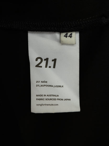A close-up of a white garment size and color label sewn onto a black garment. The label reads 21.