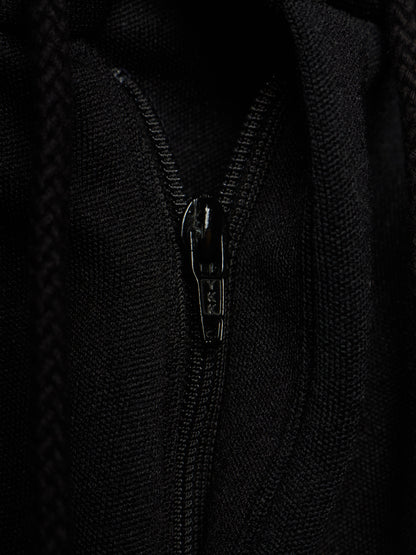 Close-up of a black zippered garment, showing the textured fabric and a black metal zipper pull with the brand name 'SAS' visible.