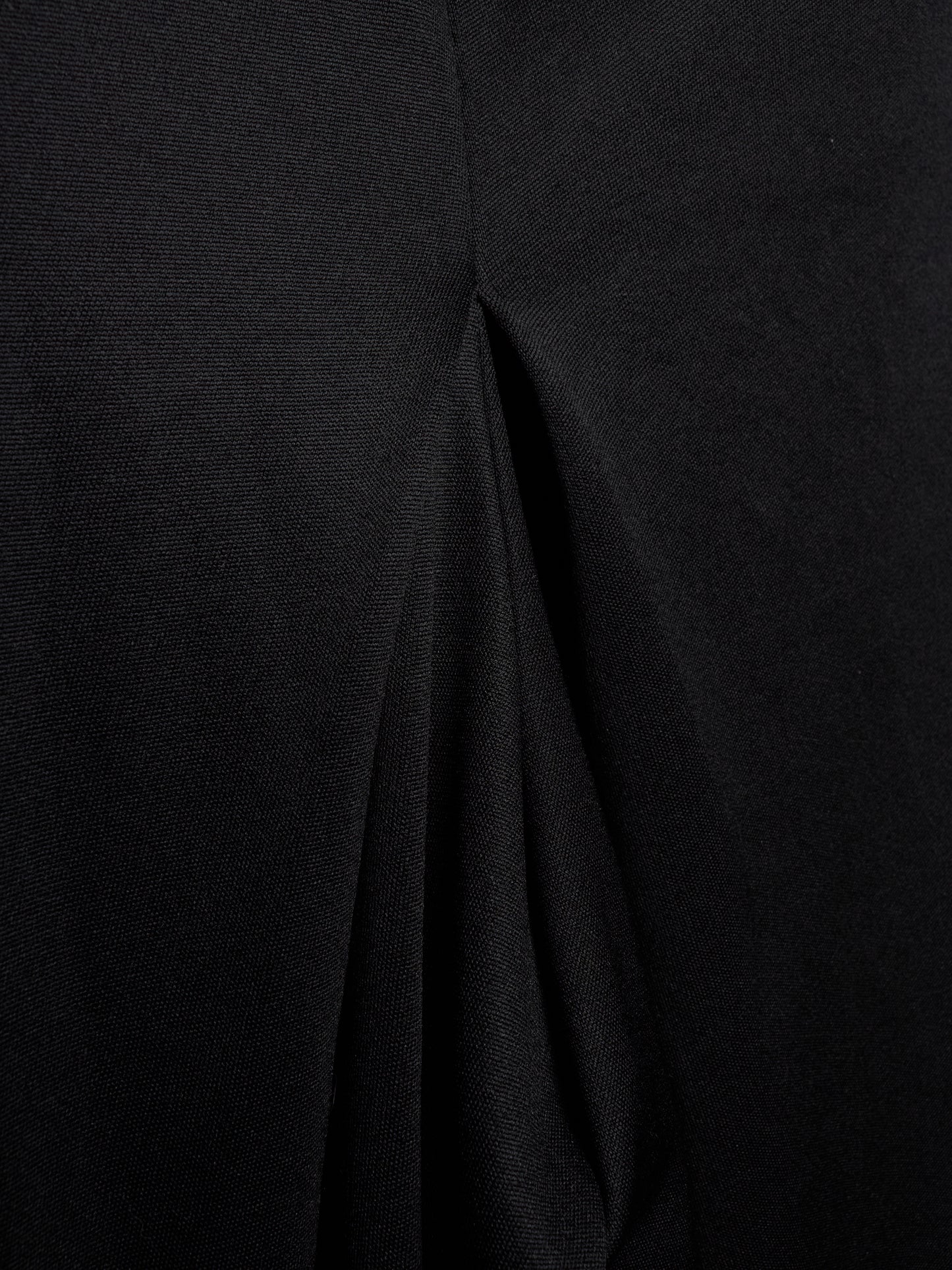 Close-up of a black textured fabric with a central seam and draped folds.