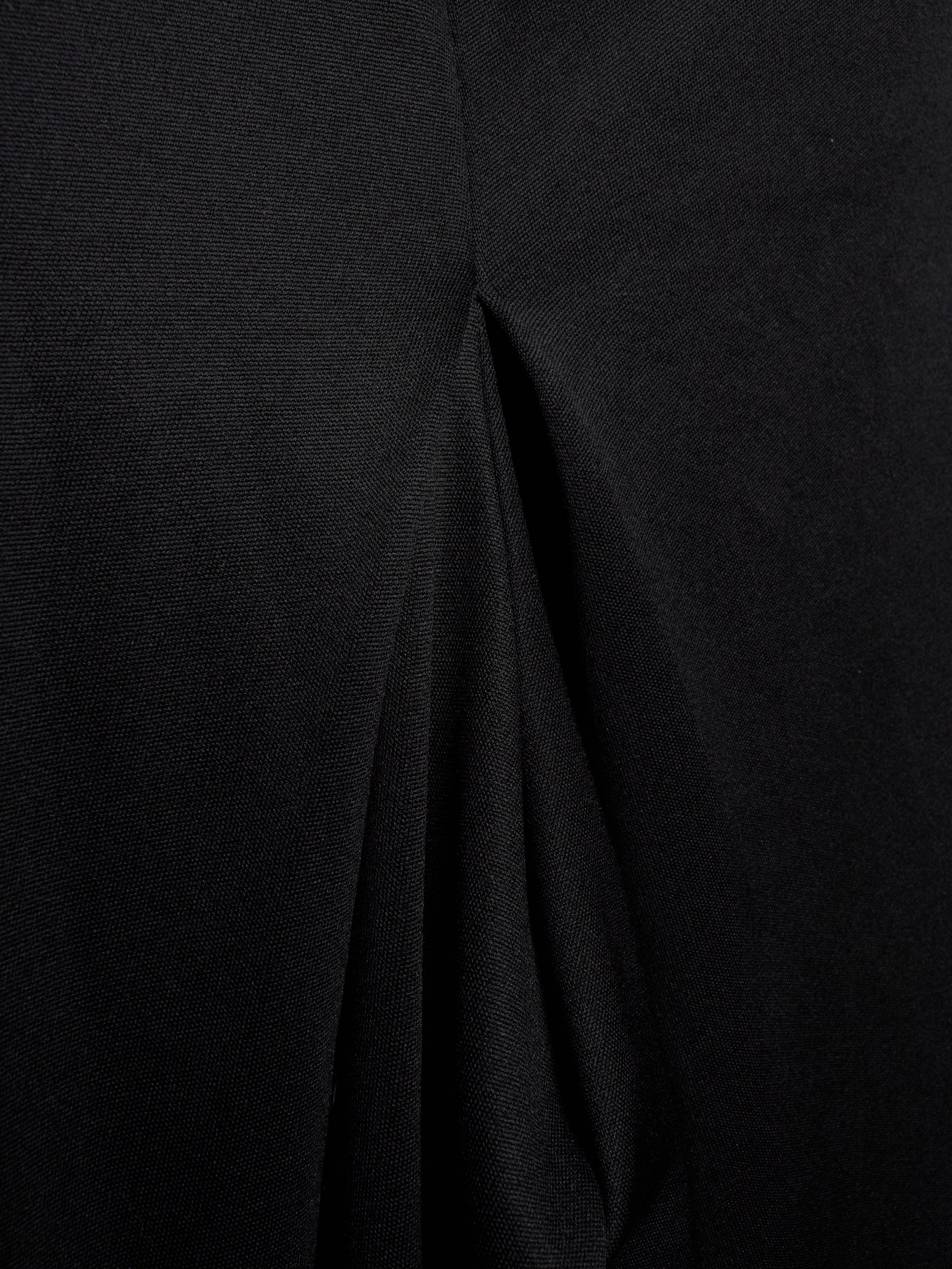 Close-up of a black textured fabric with a central seam and draped folds.